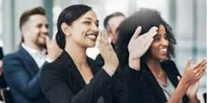 A group of colleagues smiling and applauding during a corporate wellness seminar